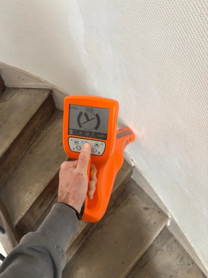 Détecteur de canalisation orange utilisé pour le traçage le long d'un mur